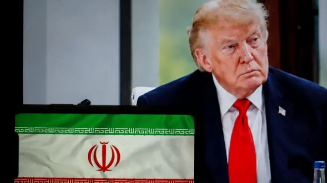 في هذه الصورة التوضيحية، يظهر الرئيس الأمريكي دونالد ترامب خلف العلم الإيراني، بينما تُعرض جميعها على الشاشات، في مدينة ليون الفرنسية بتاريخ 2 يوليو/تموز 2026