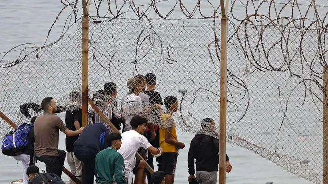 Migrantes cruzan una valla en Ceuta