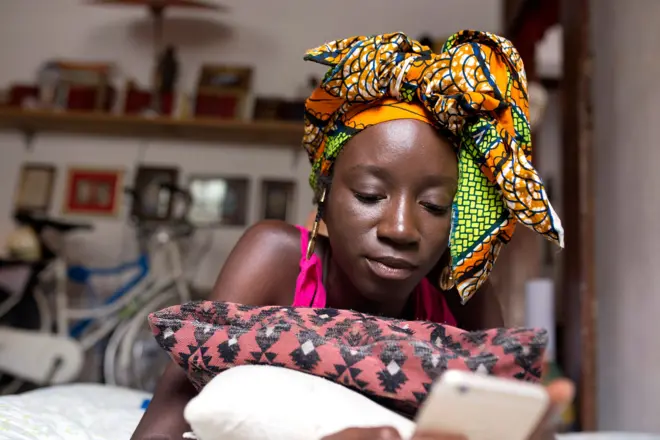 One young lady lie on one bed wit phone for her hand.