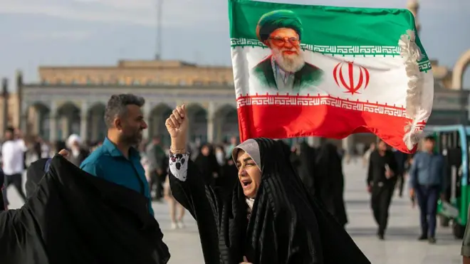 Seorang perempuan terlihat membawa bendera dengan gambar mantan Pemimpin Tertinggi Iran, Ayatollah Ali Khamenei selama Idul Adha pada 26 Mei 2026 di Qom, Iran. 
