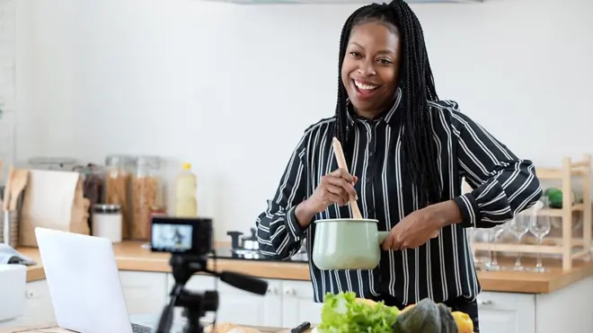 African american woman cooking vlogger recording video in kitchen at home