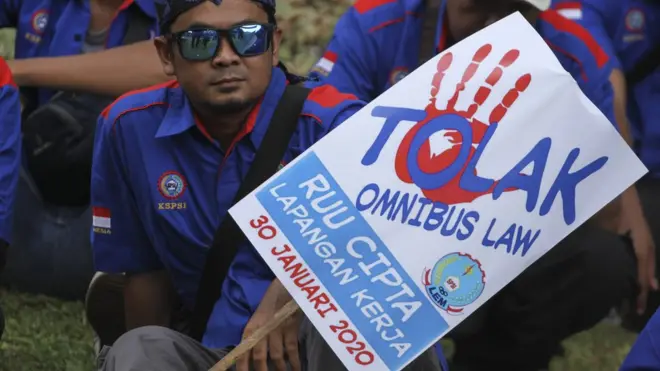 Seorang demonstran membawa poster Tolak Omnibus Law saat mengikuti aksi unjuk rasa di Depan Istana Merdeka, Jakarta, Kamis (30/01).