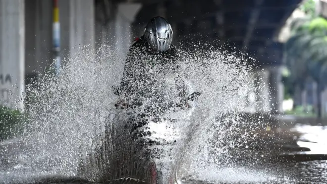 Pengendara sepeda motor mencoba melintasi banjir di Jalan Yos Sudarso, Kelapa Gading, Jakarta Utara pada MInggu (23/02).