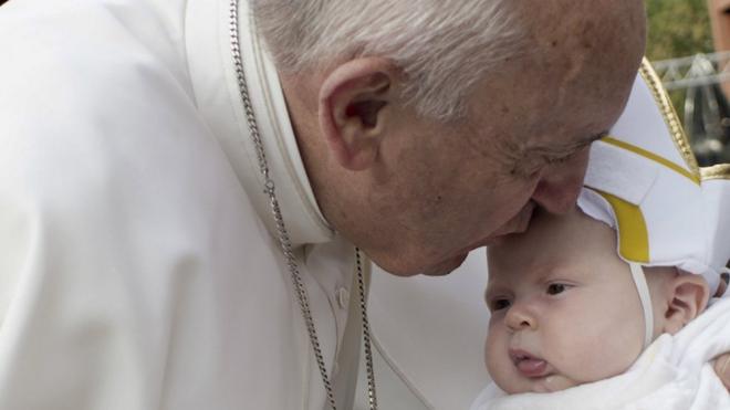 Pope Francis kisses a baby dressed as the Pope on his way to the Independence Mall in Philadelphia