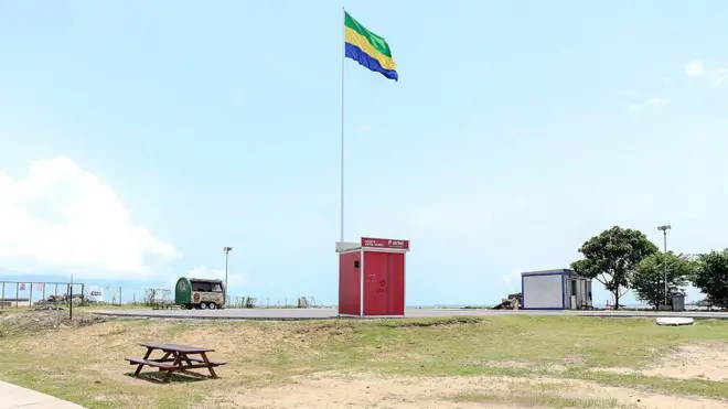 Une baraque sur laquelle est issé le drapeau gabonais sur une plage.