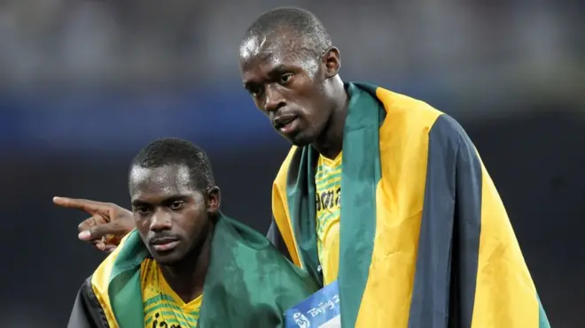 Усейн Болт (справа) лишился медали из-за партнера по забегу Несты Картера (слева)