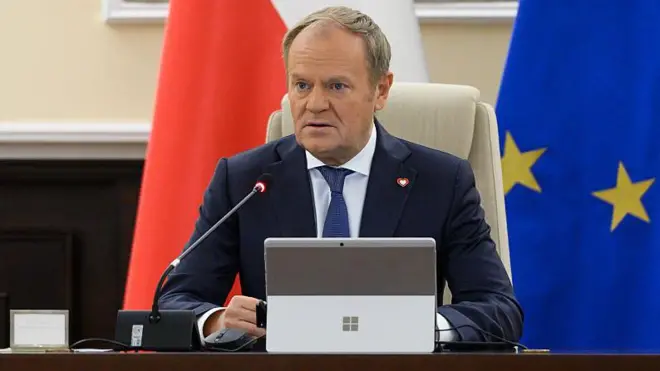 Дональд Туск за столом перед мікрофоном