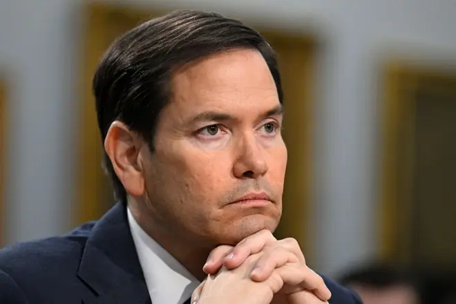 Marco Rubio observando algo com olhar sério e mãos sob o queixo