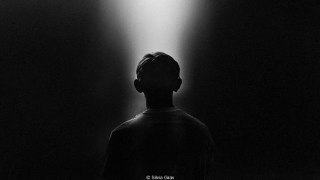 Foto en blanco y negro de una persona mirando una luz. Foto: Silvia Grav.