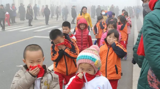 Children in Binzhou near the industrial port of Tianjin covering their noses on Wednesday amid heavy smog