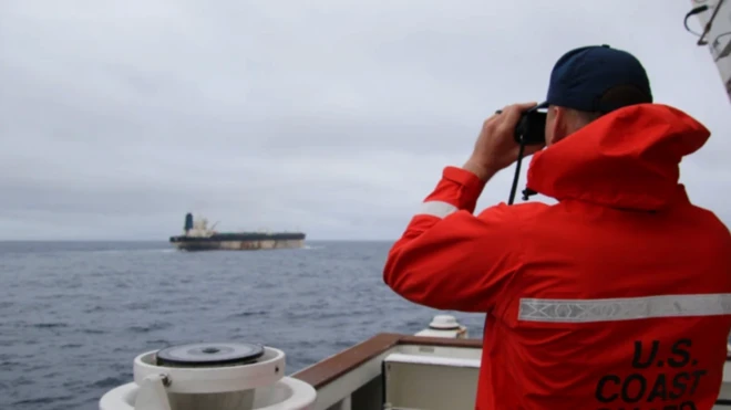 Petrol tankeri geminin Sahil Güvenlik Komutanlığı gemisinden takip edilişi görülüyor. Bir kırmızı üniformalı asker elinde dürbünle ilerideki gemiyi takip ediyor.
