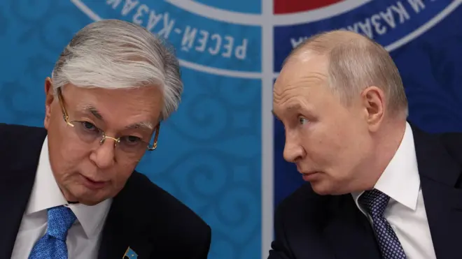 Токаев и Путин за столом о чем-то говорят.