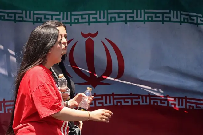 Hai người phụ nữ đi ngang qua quốc kỳ Iran tại quảng trường Vanak ở Tehran vào ngày 10/6/2026