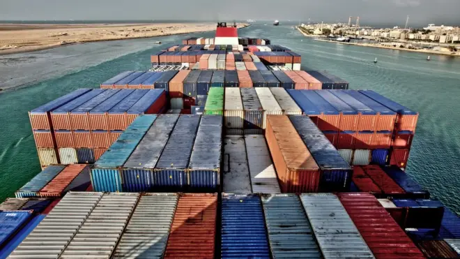 View across the deck of a container ship entering the Suez Canal, Egypt, (with the city of Suez at upper right)