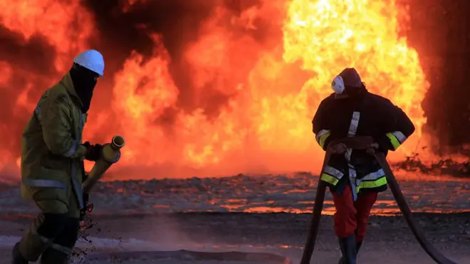 عمال نفط ليبيون يحاولون إطفاء حريق في منشأة نفطية في منطقة رأس لانوف، عقب هجمات شنها تنظيم الدولة الإسلامية