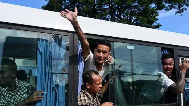 လွတ်ငြိမ်းပေးခံရသူတွေကို တင်ဆောင်လာတဲ့ ကားပြတင်းပေါက်ကနေ အင်္ကျီအဖြူရောင်ဝတ်ထားတဲ့ ကိုရန်နောင်ကြည်ဝင်းက အပြင်ကို လက်ဝှေ့ယမ်းနုတ်ဆက်နေတဲ့မြင်ကွင်း 