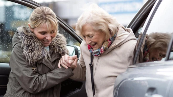 امرأة تساعد مُسنّة