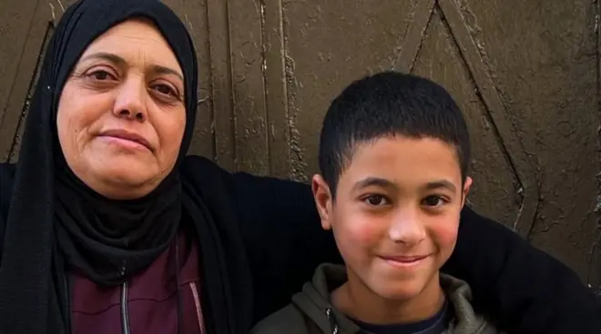 Falestin Nakhle with her arm around Karim, sitting on a doorstep