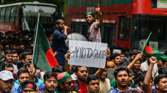 অনেক মানুষের ভিড়ের মধ্যে 'সে নো টুে কোটা' লিখা একটি পোস্টার দুই হাতে ওপরে ধরে রেখেছেন একজন। পাশে দুই জনের হাতে বাংলাদেশের পতাকা। ভিড়ের মধ্যে অনেকের মাথায়ও পতাকা বাঁধা। লোকজনের পেছনে লাল-সবুজ রংয়ের দুটি বাস। 