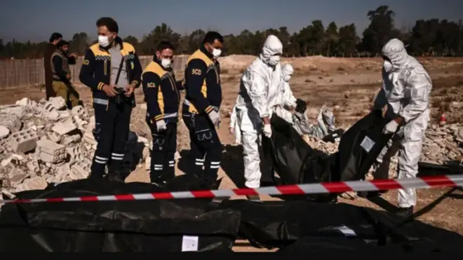 أفراد من (الخوذ البيضاء) ينقلون أكياس جثث تحتوي على رفات بشرية تم انتشالها من مقبرة جماعية في دمشق