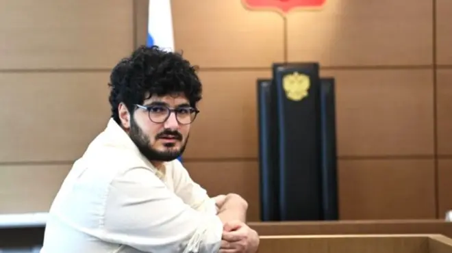 Армен Арамян, мужчина с черными волосами и бородой в белой рубашке в зале суда в 2022 году