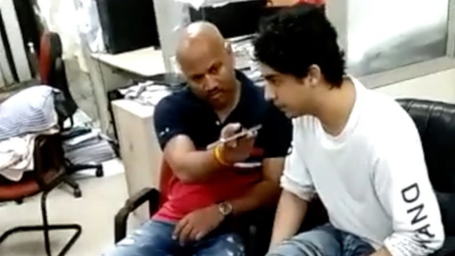 این سی بی کی حراست کے دوران گوسوائی آرین خان کے پاس نظر آ رہے ہیں اور بظاہر ان کی کسی سے بات کرا رہے ہیں