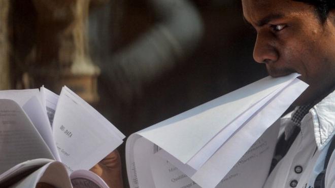 An Indian youth looks through papers as he stands in a queue to apply for a job at a jobs fair in Mumbai on October 12, 2011.