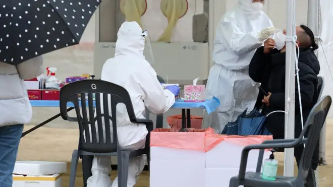 겨울비가 내린 27일 오후 대구 달서구 두류공원에 마련된 임시선별진료소에서 우산을 든 시민들이 줄지어 코로나19 진단검사를 기다리고 있다