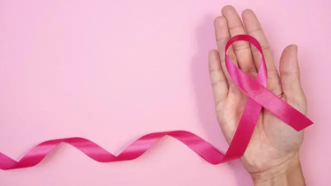 Кампања за борбу против рака дојке са ружичастом траком, Жена држи ружичасту траку на ружичастој позадини. 