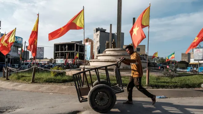 የትግራይ ክልል እና የኢትዮጵያ ባንዲራዎች በተሰቀበሉበት አደባባይ በኩል የሚያልፍ ወጣት