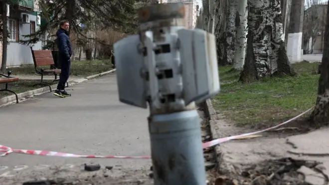 مردی از کنار دم منفجر نشده موشکی که به نظر حاوی بمب‌های خوشه‌ای در اوکراین است می‌گذرد