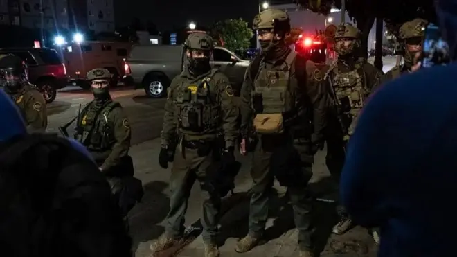 Mudaaharaadyada looga soo horjeedo ugaarsiga lagu hayo dadka muhaajiriinta ah ee Los Angeles ayaa sii socda maalintii saddexaad, iyadoo boolisku ay sheegeen in magaalada hoose ee LA ay hadda tahay aag uu ka dhacaya "kulan sharci darro ah