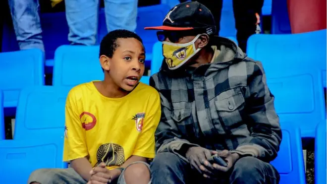 ተክሌ አበራ የጨዋታውን እንቅስቃሴ ከሚነግረው ታዳጊ ጋር በስታዲየም