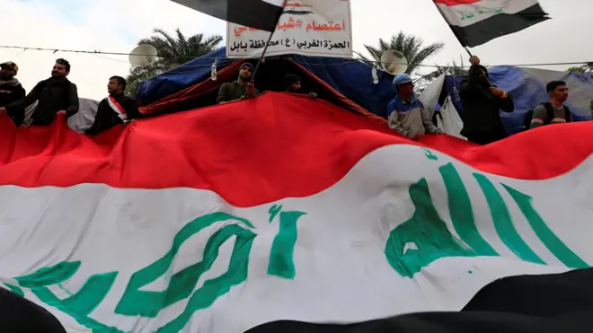 متظاهرون يرفعون علم العراق