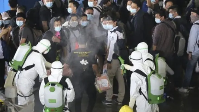 Petugas menyemprotkan cairan desinfektan kepada WNI kru kapal World Dream saat menaiki KRI dr Soeharso yang difasilitasi TNI AL, di Selat Durian Kepulauan Riau, Rabu (26/2/2020).