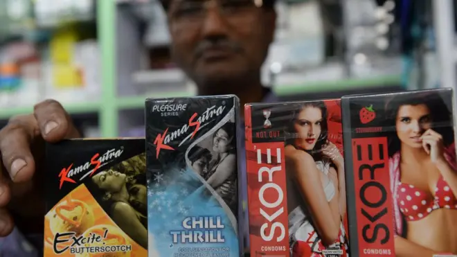 An Indian shopkeeper arranges condom packets at a chemist shop in New Delhi on April 27, 2016.