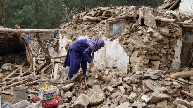 Khost, Afghanistan. Woman surrounded by rubbles.