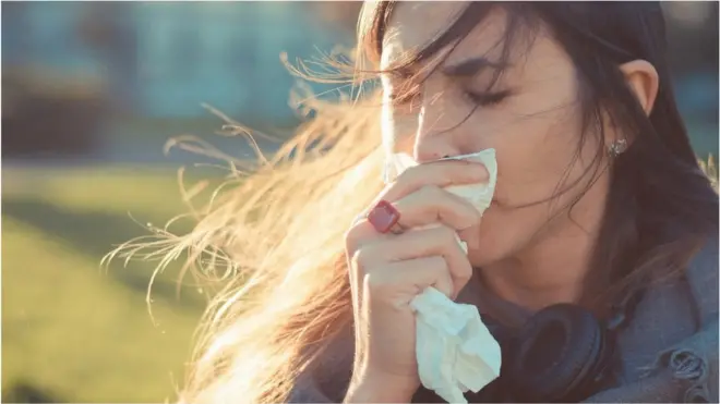 Woman holding a tissue to her nose