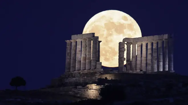 The full moon rises behind Temple of Poseidon near Athens in Greece