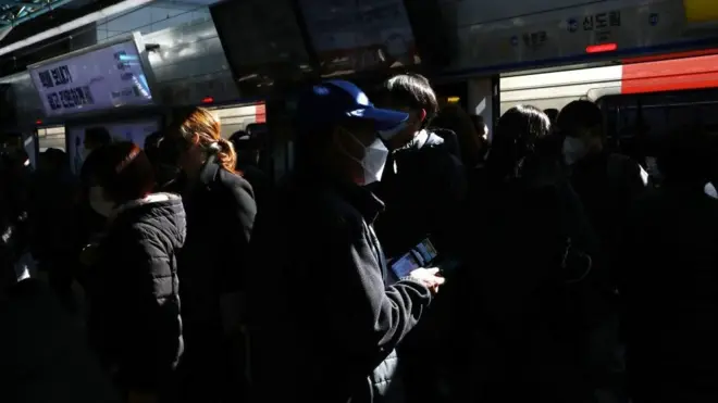 마스크를 쓰고 지하철 역에서 열차 대기 중인 시민