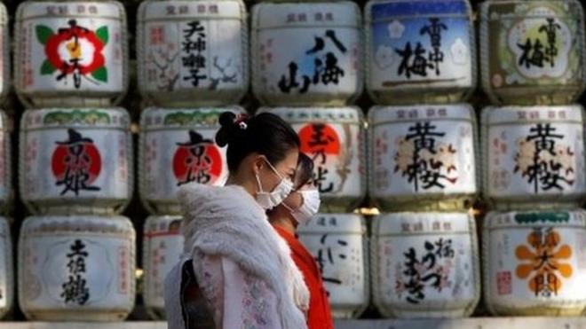 Kimono-clad women wearing protective face masks walk in front of Japanese Sake barrel decorations for the year-end and New-Year at Meiji Shrine, amid the coronavirus disease (COVID-19) outbreak, in Tokyo, Japan, December 31, 2020.