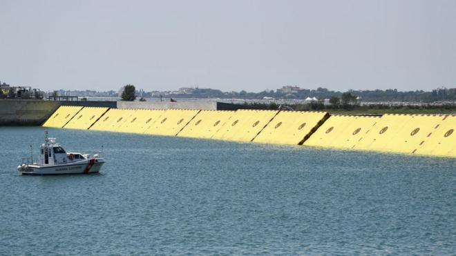 Yellow mobile barriers are seen above the surface of the water during tests of flood barrier project Experimental Electromechanical Module (Mose)