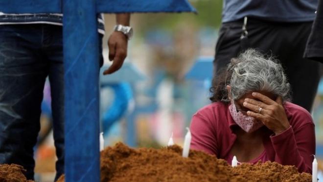 A woman reacts during a mass burial of people who passed away due to the coronavirus in Manaus