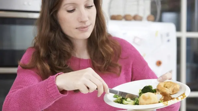Mujer tirando sobras de comida a la basura