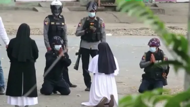 Sister Ann Rose Nu Tawng kneels in front of police officers to them to refrain from violence against children and residents