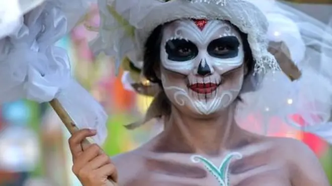 A woman in skeleton make-up carries and umbrella