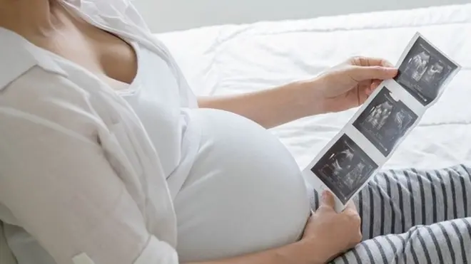 અલ્ટ્રાસાઉન્ડ રિપોર્ટને જોતી મહિલા