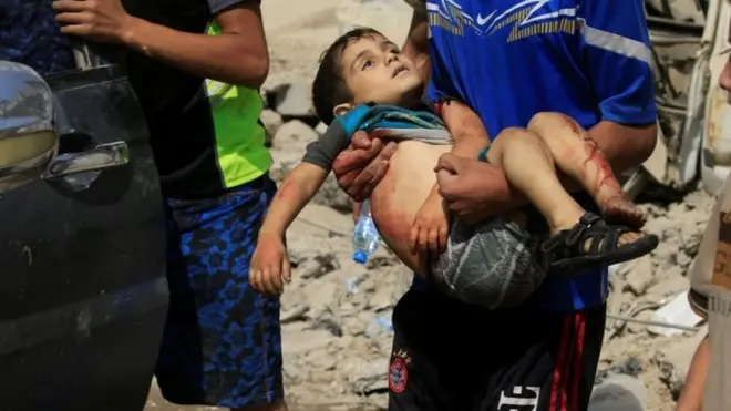 A displaced Iraqi man who fled from clashes, carries a wounded child in western Mosul. Photo: 3 June 2017