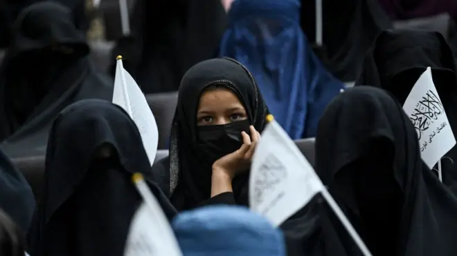 Siswa bercadar memegang bendera Taliban saat mereka mendengarkan pembicara sebelum pawai pro-Taliban di Universitas Pendidikan Shaheed Rabbani di Kabul pada 11 September 2021.