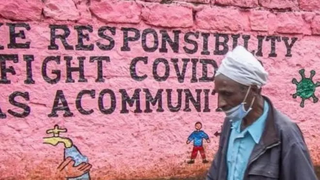 رجل يمر بجوار جدار مرتديا كمامة